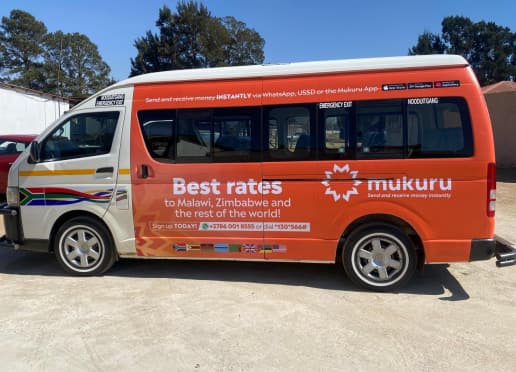 Minibus taxi wrapped in orange Mukuru "Best rates" branding