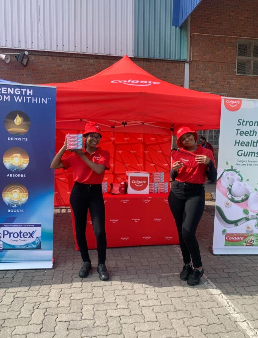 Two promoters in red at a Protex branded gazebo outside a store