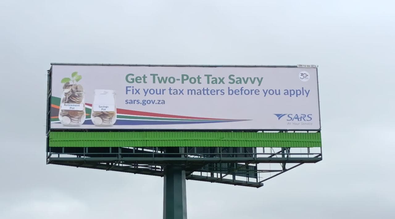 SARS "Get Two-Pot Tax Savvy" billboard on a tall steel pole above a green fence